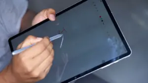Eine Person schreibt mit einem Stylus auf einem digitalen Tablet und hebt moderne Technologie und Kreativität hervor.